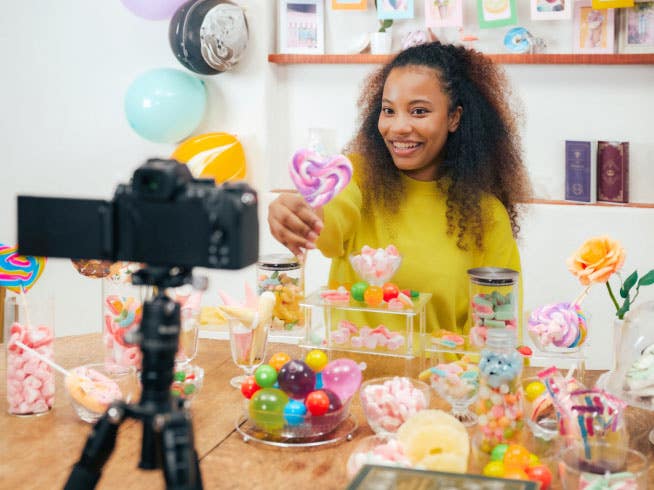 Young woman holding colourful lollipops up to the Nikon Z50II Mirrorless camera. | Nikon Cameras, Lenses & Accessories